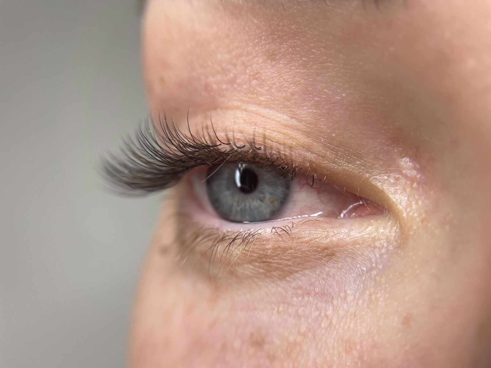 Van opzij: een natuurlijke set wimperextensions bij een klant met blauwgrijze ogen