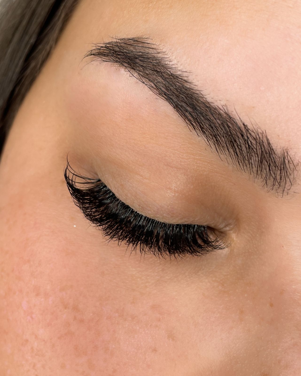 Een volle set wimperextensions op een gesloten oog, van dichtbij